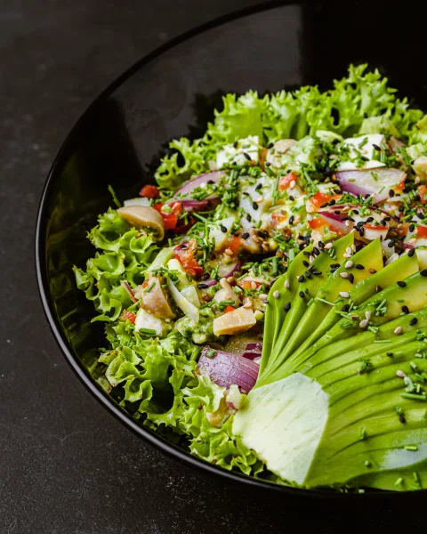 Ensalada con palta en bowl negro vista cercana.