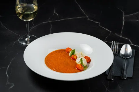Entrada gastronómica con salsa naranja y vegetales.