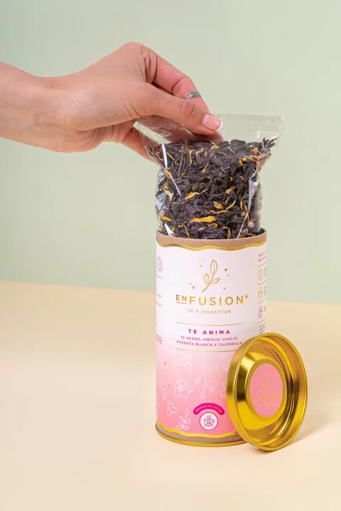 Envase de té con hebras visibles en una composición de tonos pastel.