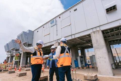 Equipo de trabajadores frente a módulo eléctrico en obra.
