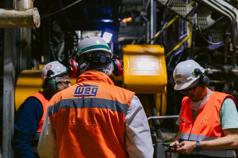 Equipo de trabajadores WEG reunido dentro de planta.