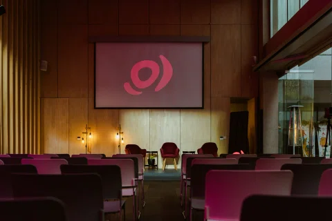 Escenario vacío preparado para una charla con iluminación rosada.