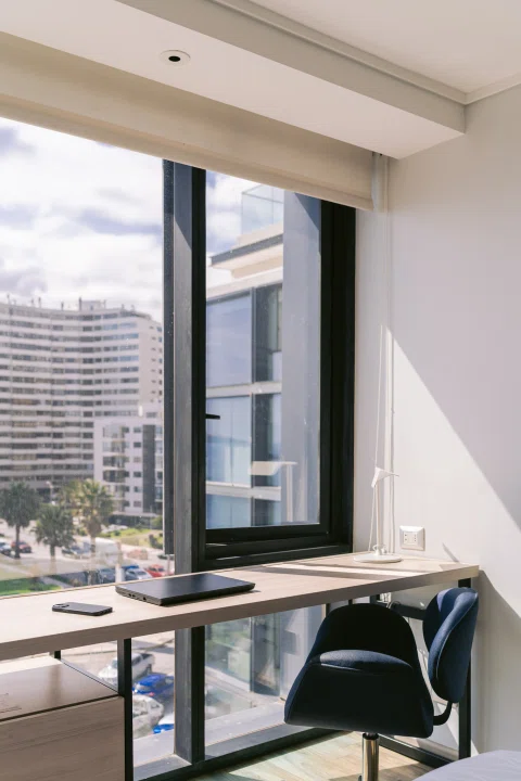 Escritorio de habitación junto a gran ventanal.