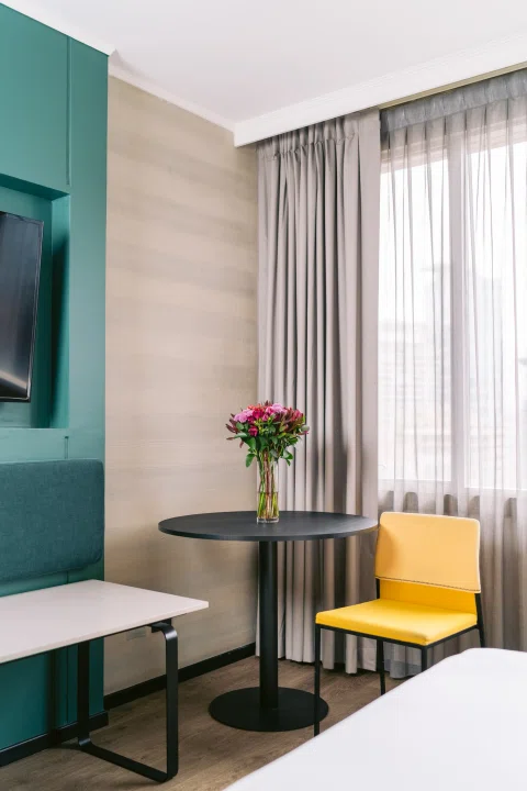 Escritorio de habitación con silla amarilla y flores.
