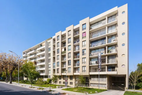 Fachada de edificio residencial de varios pisos con balcones y áreas verdes.