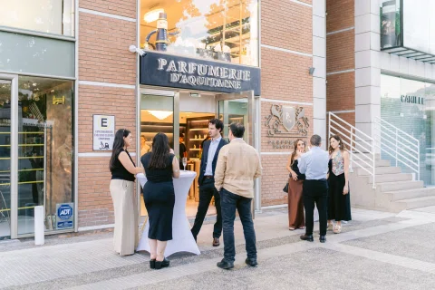 Invitados se reúnen frente a la fachada de una perfumería durante su inauguración.