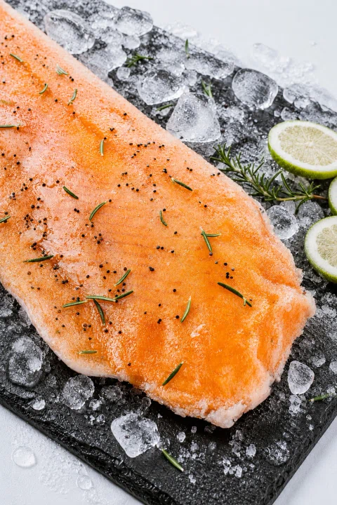 Filete de salmón sazonado sobre pizarra con hielo.
