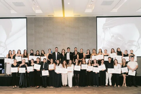 Grupo posa en escenario mostrando certificados de participación.