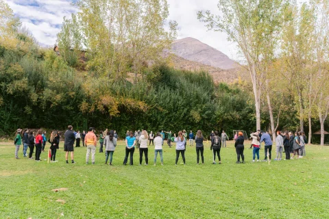 Grupo forma un círculo durante una actividad al aire libre.
