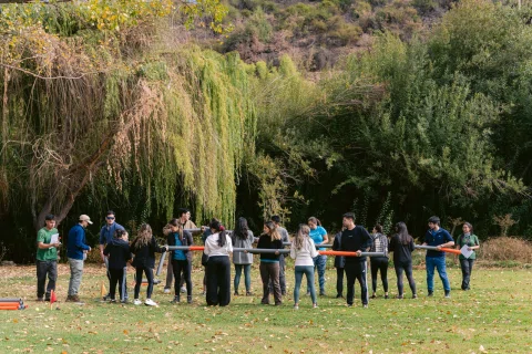 Participantes realizan una dinámica grupal en círculo al aire libre.
