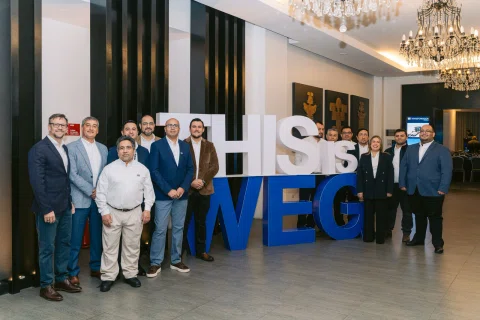 Grupo de ejecutivos posa frente a una instalación con letras de WEG.