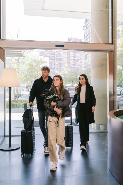 Grupo de huéspedes llegando al hotel con maletas.