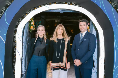 Tres invitados posan en la entrada de una celebración corporativa.
