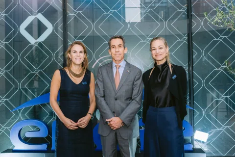 Tres invitados posan frente a un fondo corporativo.