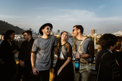 Asistentes conversan durante un evento al aire libre al atardecer.