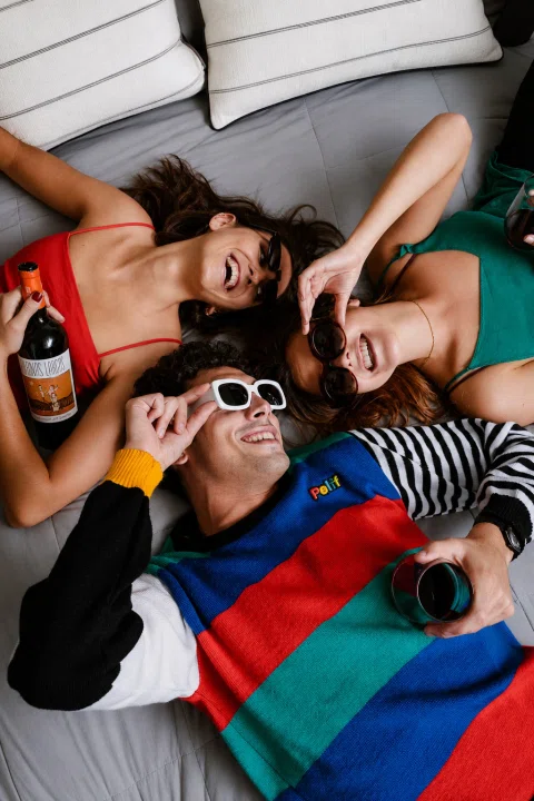 Grupo de jóvenes comparte vino en una escena lifestyle sobre una cama.