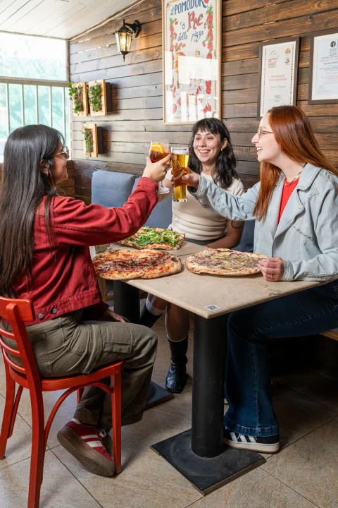 Grupo de mujeres comiendo y brindando en mesa.
