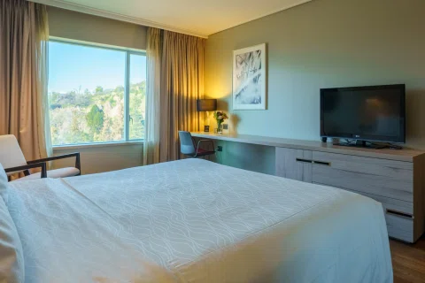 Habitación con cama y vista urbana desde ventana.
