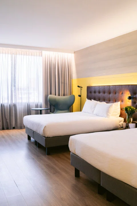 Habitación doble con dos camas y sillón amarillo.