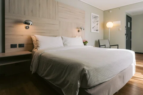 Habitación matrimonial con cama blanca y luz cálida.