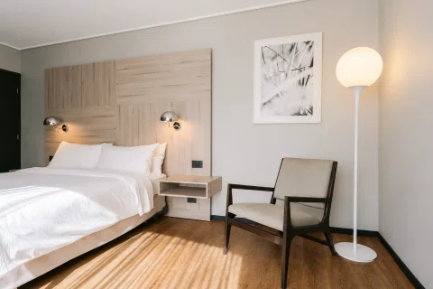 Habitación matrimonial con cama sillón y lámpara de pie.