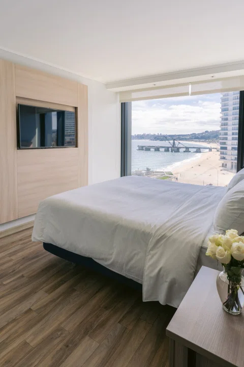 Habitación matrimonial con cama junto a ventanal.