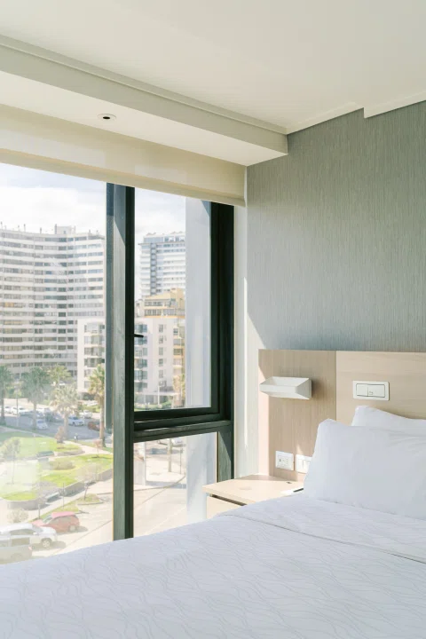 Habitación matrimonial con ventanal y vista urbana.
