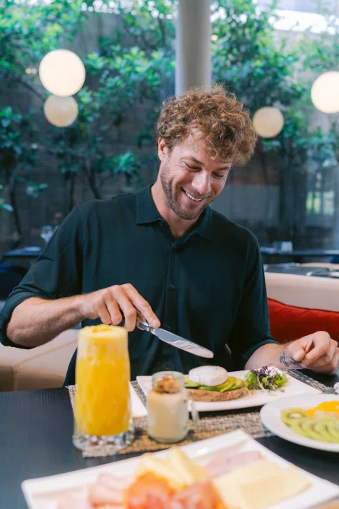 Hombre desayunando con jugo en mesa.
