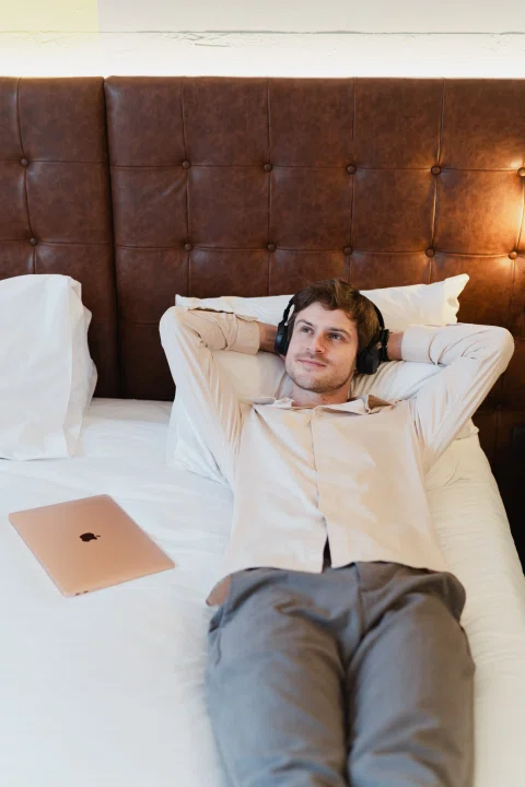 Hombre recostado sobre cama con notebook al lado.