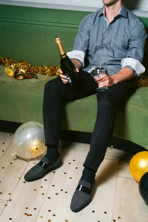 Hombre sentado con botella de espumante y globos.