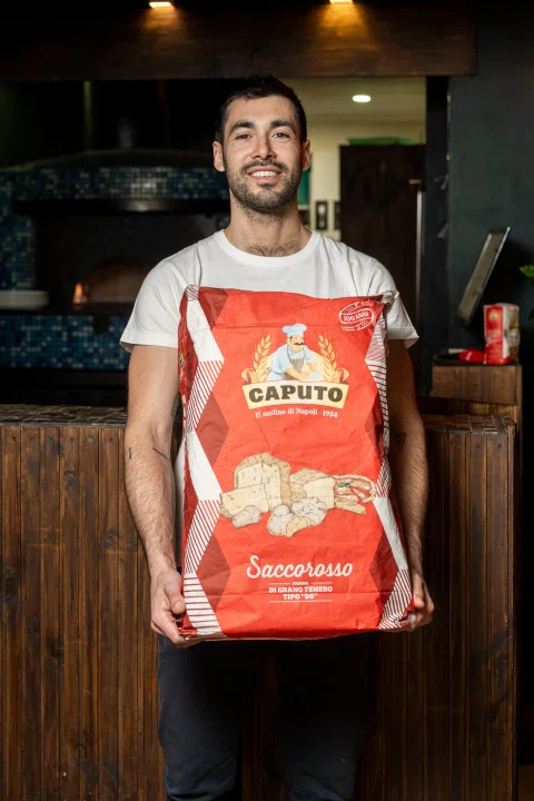Hombre sosteniendo saco de harina Caputo.