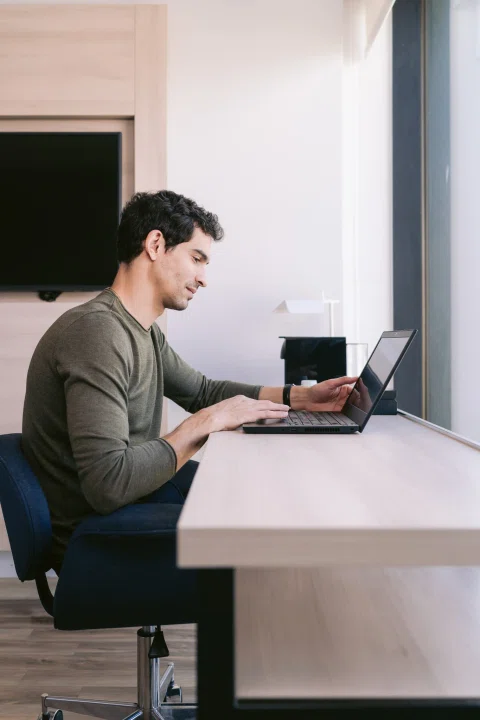 Hombre trabajando con notebook en escritorio de habitación.