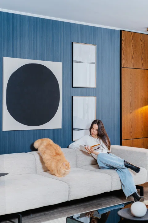 Habitación de hotel con una huésped y un perro sobre el sofá.