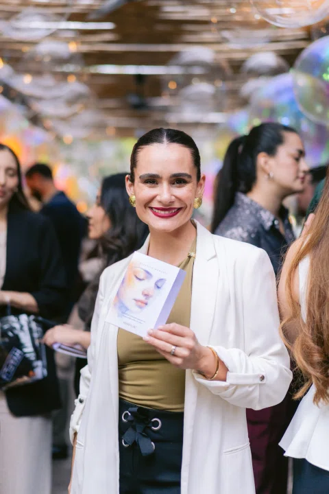 Invitada con credencial sostiene una copa durante un encuentro social.