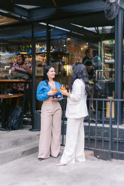 Dos invitadas conversan en el exterior durante la recepción del evento.