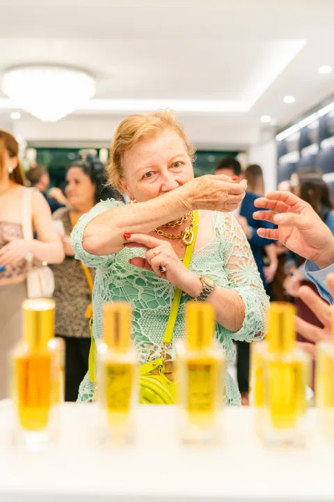 Invitadas prueban fragancias frente a una exhibición de productos.