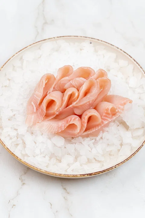Láminas de pescado crudo servidas sobre hielo.
