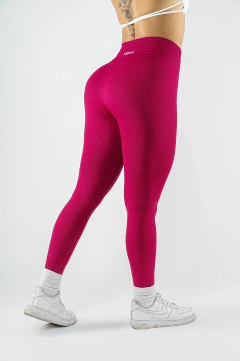 Modelo muestra leggings deportivos rosados sobre fondo blanco.