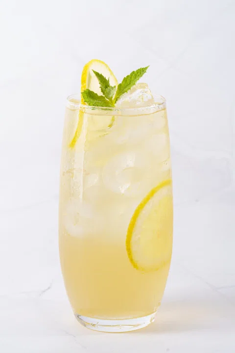 Limonada con limón y menta servida en un vaso alto.
