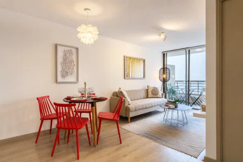 Living comedor de departamento con sillas rojas y balcón.