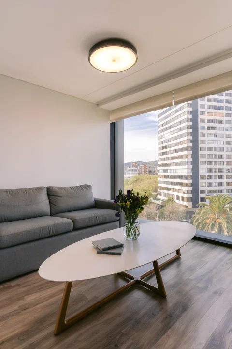 Living de suite con sofá mesa y ventanal.
