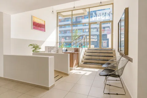 Lobby de edificio con escalera, ventanal y área de espera.