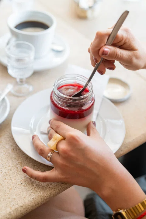 Mano agregando salsa roja a postre en vaso.