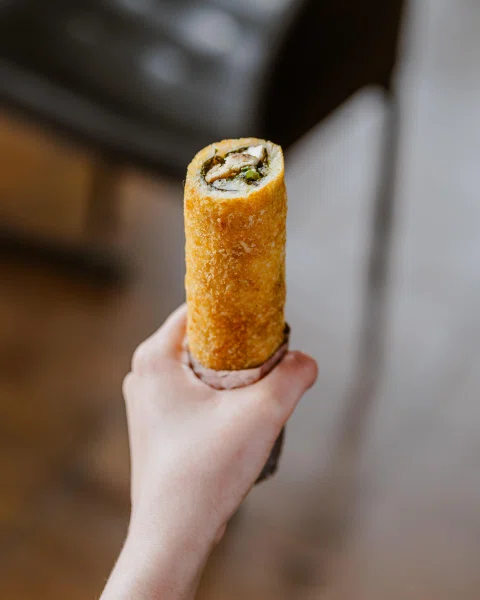 Mano sosteniendo roll frito tipo burrito.