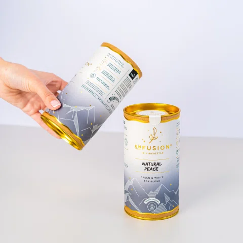 Mano vertiendo contenido entre dos latas de infusión.