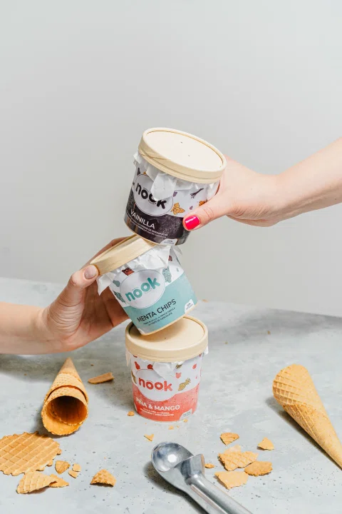 Manos apilando potes de helado Nook con conos alrededor.