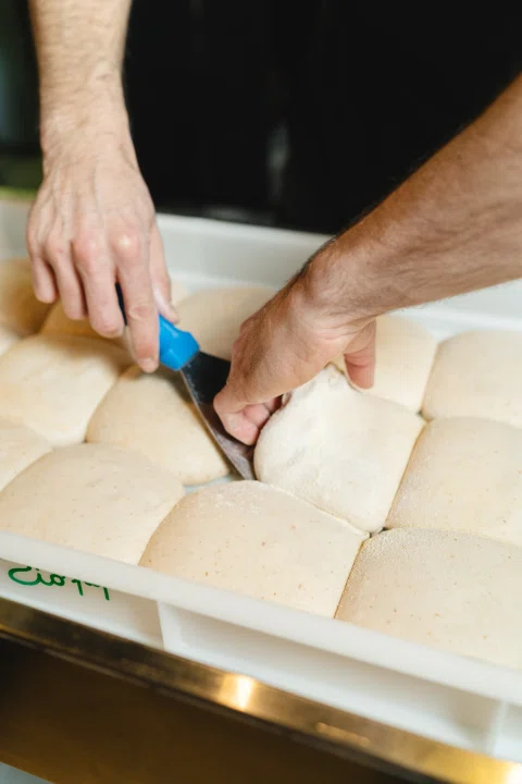 Manos cortando porciones de masa.