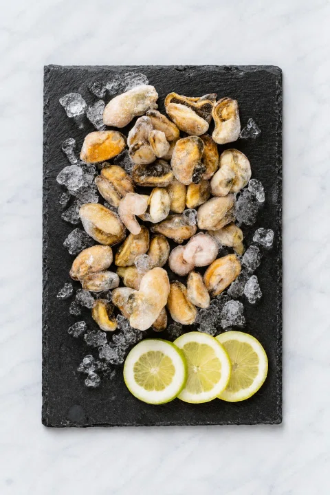 Mariscos cocidos sobre pizarra negra con limón.