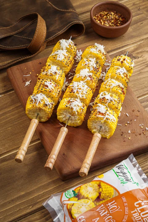 Mazorcas de maíz en brochetas con condimentos.