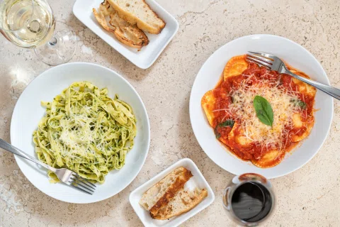 Mesa cenital con pasta verde y plato con salsa roja.